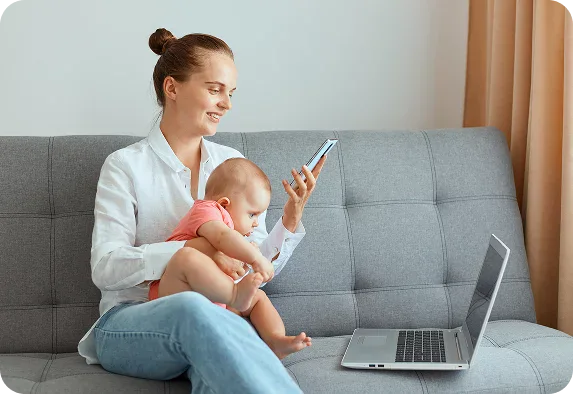 Eine Frau sitzt auf einem grauen Sofa, hält ein Baby auf dem Schoß und sucht lächelnd auf ihrem Smartphone nach Tipps der SEO-Agentur Rastatt. Ein aufgeklappter Laptop liegt vor ihr auf dem Sofa. Eine Frau sitzt auf einem grauen Sofa, hält ein Baby auf dem Schoß und sucht lächelnd auf ihrem Smartphone nach Tipps der SEO-Agentur Rastatt. Ein aufgeklappter Laptop liegt vor ihr auf dem Sofa.