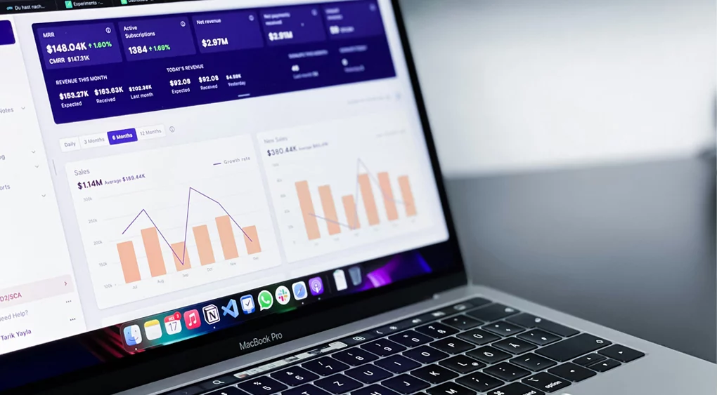 Auf einem MacBook Pro werden Datenanalyse-Dashboards mit Diagrammen, Grafiken und Statistiken einer Website angezeigt, auf der kürzlich eine Inhaltsprüfung durchgeführt wurde. Der Schwerpunkt liegt auf geschäftlichen Kennzahlen wie Umsatz und Abonnentenzahlen. Der Laptop steht auf einem weißen Schreibtisch.