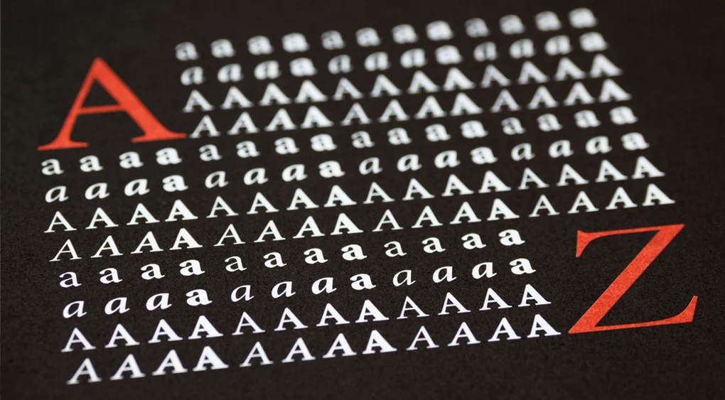 Auf schwarzem Hintergrund sind Reihen weißer Großbuchstaben „A“ zu sehen, die an die schlichte Typografie von Google Fonts erinnern. Oben links befindet sich ein großes rotes „A“ und unten rechts ein großes rotes „Z“. Ein „A“ im oberen Bereich ist leicht geneigt, was dem geordneten Layout einen subtilen optischen Reiz verleiht.
